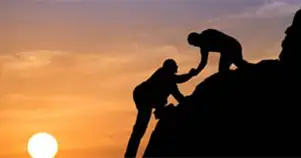 Silhouette of a climber helping another up the hill